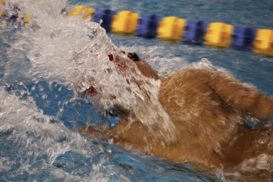 Freshmen Kai Brownlee pushes to the end of the pool while competing in a swim relay.