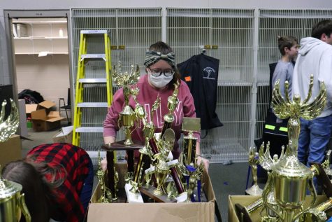 Color guard member and flutist Megan Gibson (10) helps move a box of old trophies.