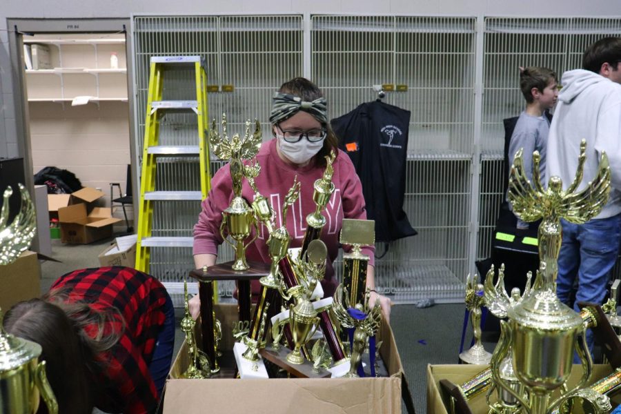 Color+guard+member+and+flutist+Megan+Gibson+%2810%29+helps+move+a+box+of+old+trophies.