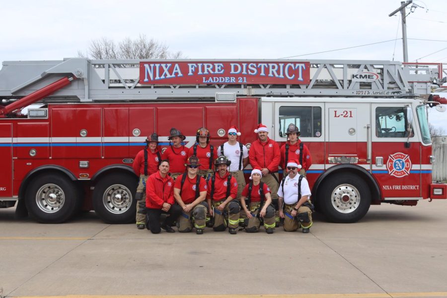 Nixa Fire Protection District firefighters pose in front of their ladder truck, dressed in Santa hats and their bunker gear