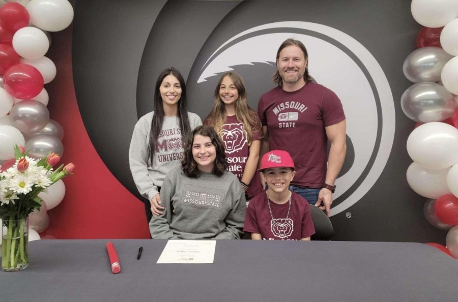 Sidnee Harp sits with her family as she signs to Missouri State University for Education on educational signing day.