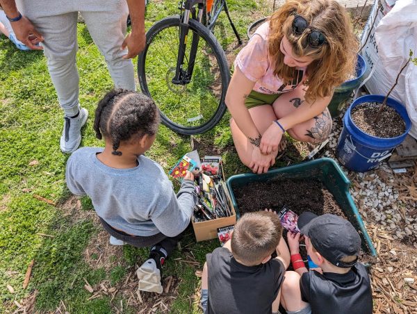 A group of children plant seeds at a SCG site. SCG offers a 4-H Club that encourages students to partake in the community-building that is found in gardening. 