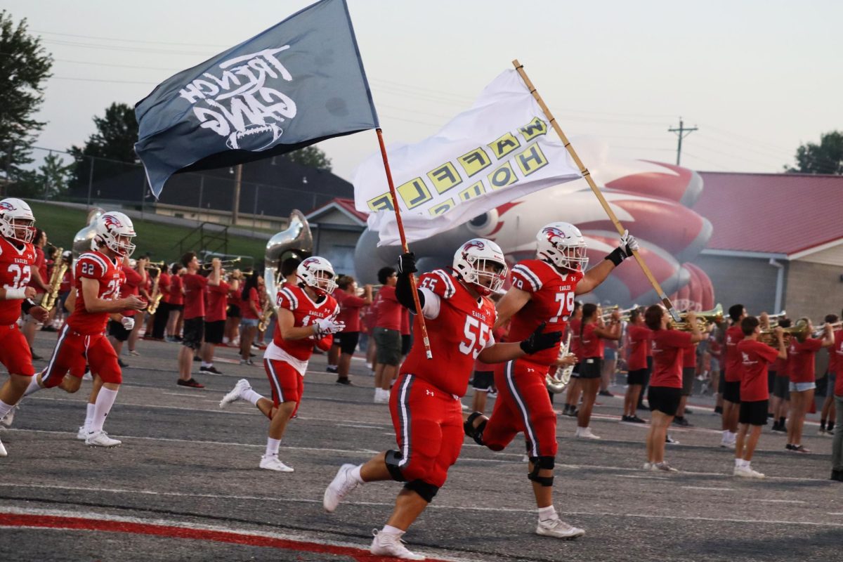 Ethan Cho carries the Trench Gang flag and Jackson Cantwell flies the Waffle House flag during the 2023 game against Webb City.  