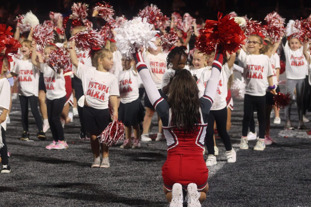 Senior cheerleader Rayelee Bachman leads the young cheerleaders in a cheer routine during halftime.