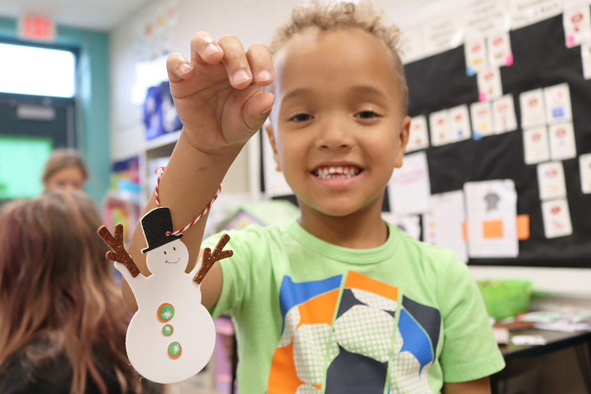 Kindergartener Brysen Headly shows off his ornamented snowman art project.