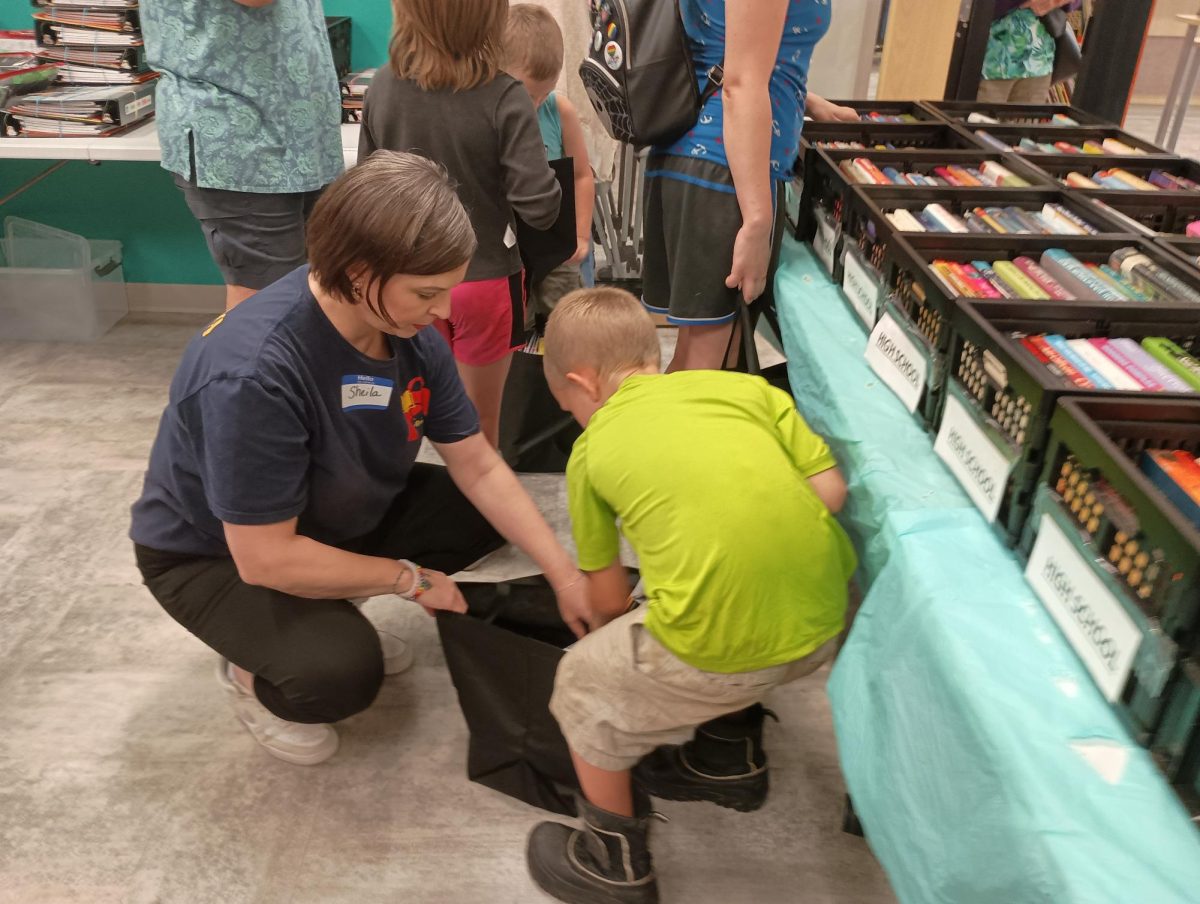 BookBag founder, Sheila Michaels, helps homeschooled first-grader Cam Zeigler load books into a bag.