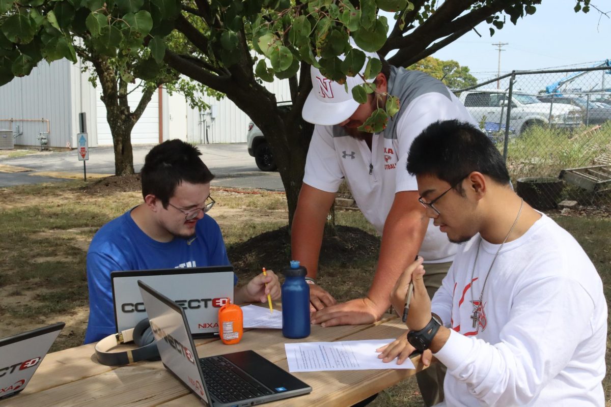 SCORE juniors Jeremy Collins (11) and Kyle  Mafnas (11) work with teacher Kenzie Medley to complete assignments outside during the day.