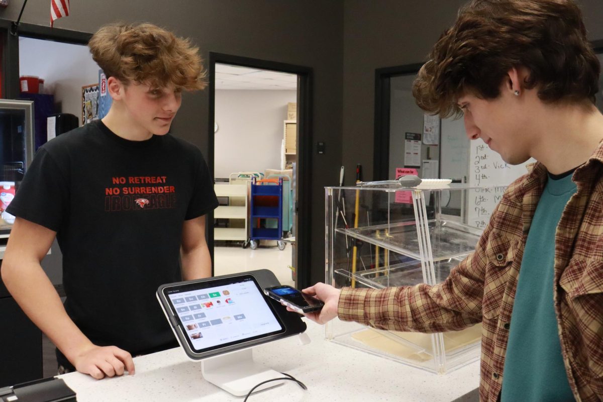 Desmond Payne watches as customer Jack Edwards uses tap to pay at the Birdhouse.