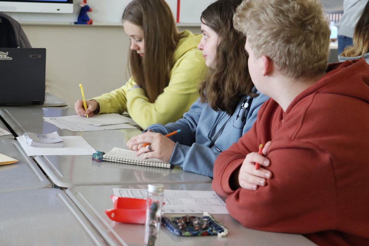 Juniors Elena Thonig, Zoe Brewer and Myles Bufford-Stark listen to George Villanueva, government teacher, immerse them in the storyline. “D&D is a very personal, social game, which tends to surprise people,” said Zoey Walker, president of Nixa’s D&D club.