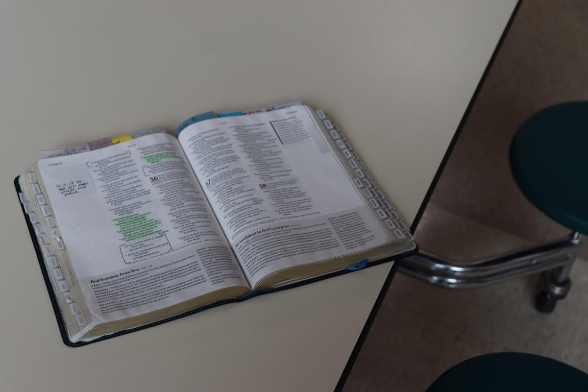  A worn Bible sits open on a cafeteria lunch table, offering a moment of quiet reflection amid the afternoon rush.